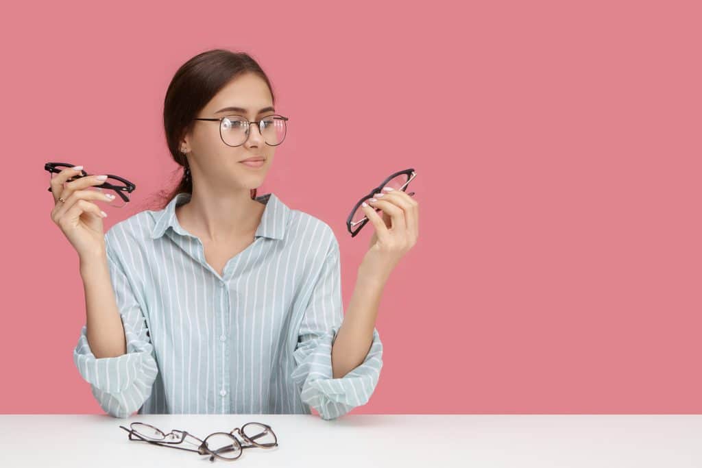 Femme hésitant entre deux montures de lunettes